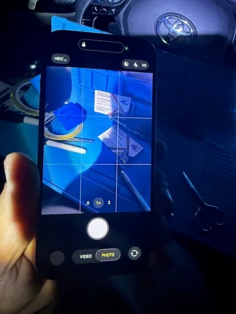 iPhone 15 camera working after iRepairMan repair — clear image of tools on blue mat during test.