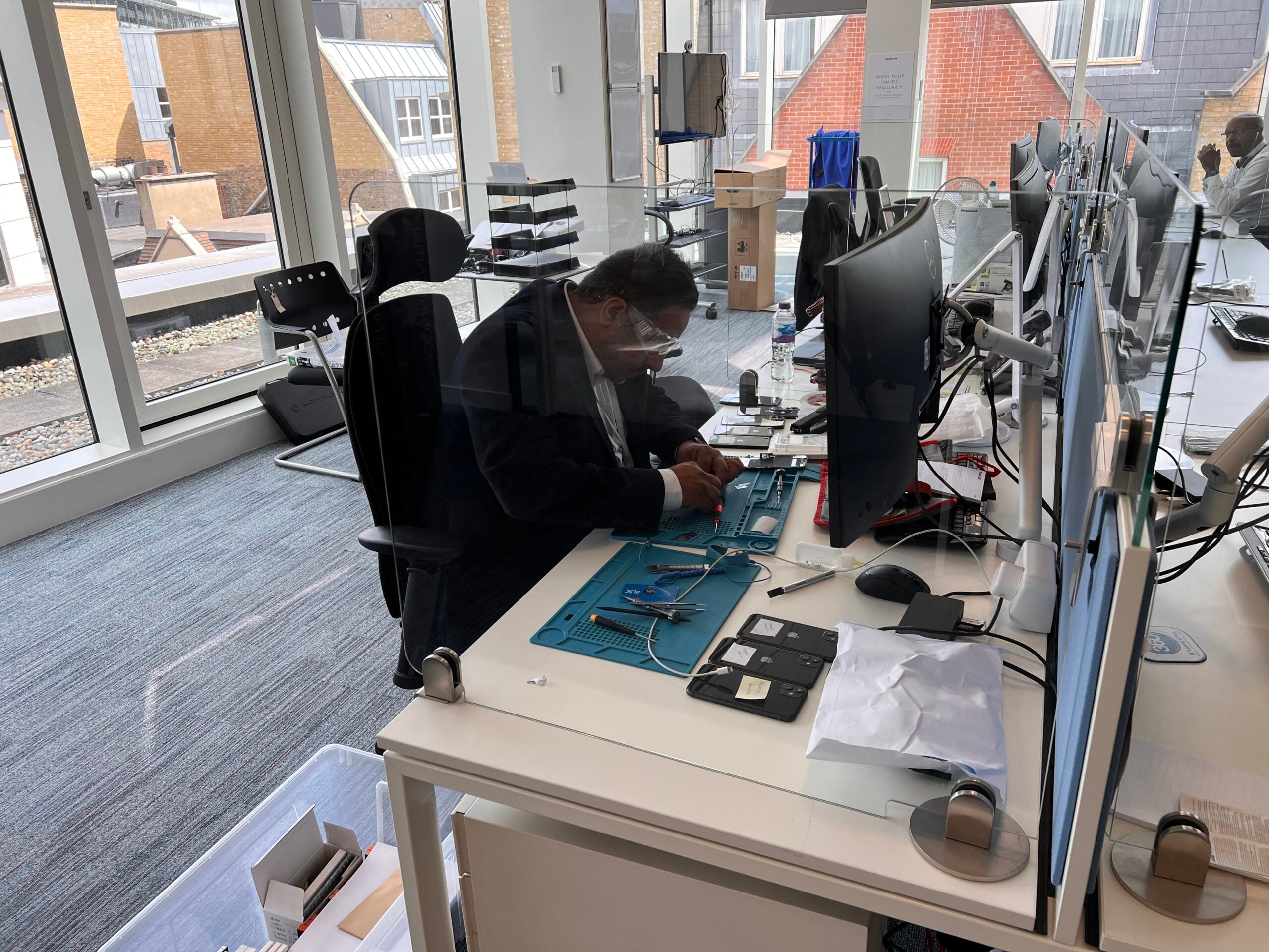 iRepairMan technician performing on-site mobile phone repairs inside a modern corporate office.