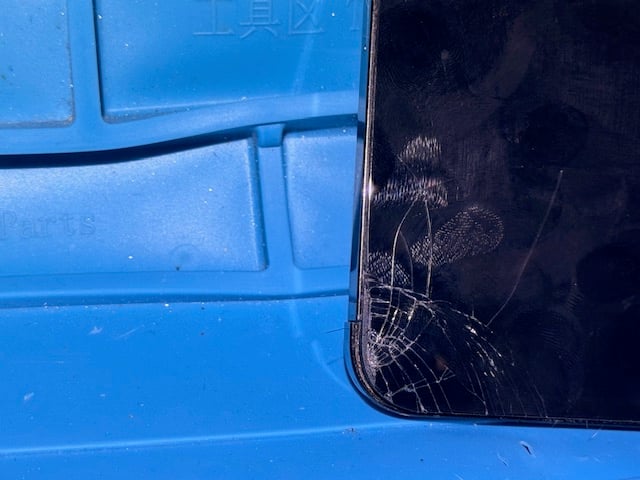 Cracked iPhone 12 Pro Max screen corner close-up before repair