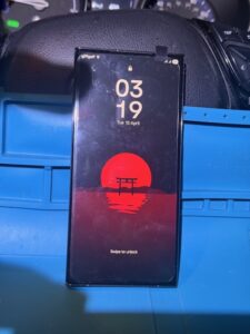 Samsung Galaxy S23 Ultra after repair with a vibrant red sunset wallpaper, showing a working display and locked screen with the time displayed