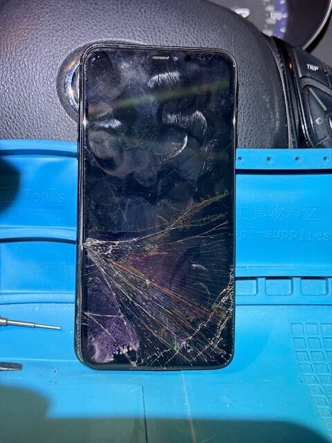Severely cracked iPhone screen before emergency night repair at a hospital
