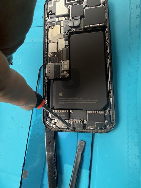 Cleaning debris from iPhone 15 Pro frame before installing new screen and water-resistant adhesive seal