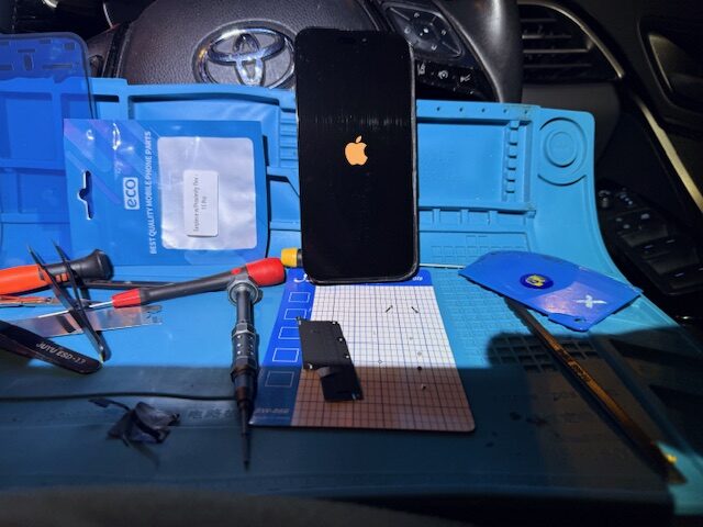 Testing new iPhone 15 Pro screen before sealing and final screw installation during London mobile repair service